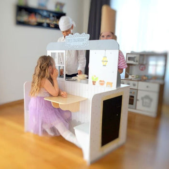 Kind speelt in de keuken van het Gerardo’s Toys 2-in-1 eetcafé, ander kind zit in het restaurantgedeelte.