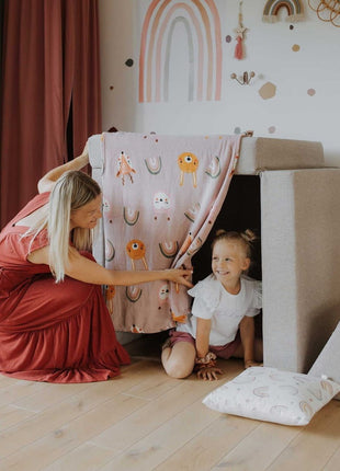 Kind en volwassene delen een speelmoment in een tentvormige opstelling van de Monboxy Montessori speelbank – bevordert ouder-kind interactie.