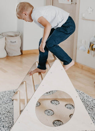 Kind klimt op de Berkenhouten Montessori Klimdriehoek in een speelkamer.