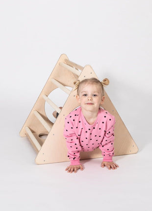 Kind kruipt door de Berkenhouten Montessori Klimdriehoek op een witte achtergrond.