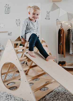 Kind zit boven op de Berkenhouten Montessori Klimdriehoek met Helling in een speelkamer.