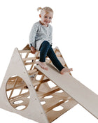 Kind zit boven op de Berkenhouten Montessori Klimdriehoek met Helling op een witte achtergrond.