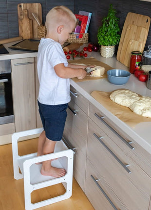 Compacte Montessori Speeltafel met Stoel gebruikt als opstapje terwijl kind kaas snijdt.
