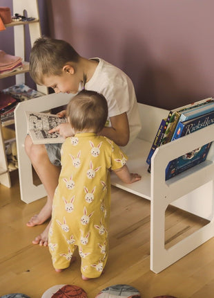 Compacte Montessori Speeltafel met Stoel waarop kind zit en boek leest met jonger kind.