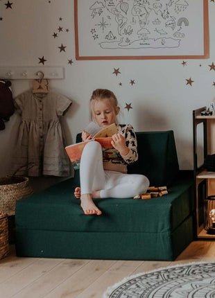Meisje leest een boek op de Monboxy Montessori speelbank in bankopstelling – rustmoment in een multifunctionele speelhoek.