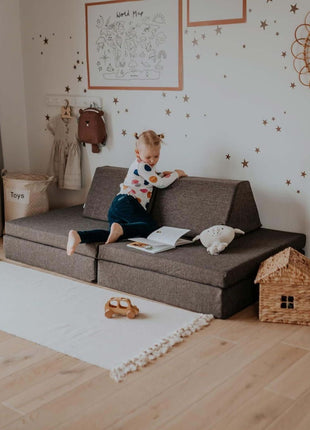 Kind leest een boek in de bankvorm van de Monboxy Montessori speelbank – bevordert concentratie en leesplezier.