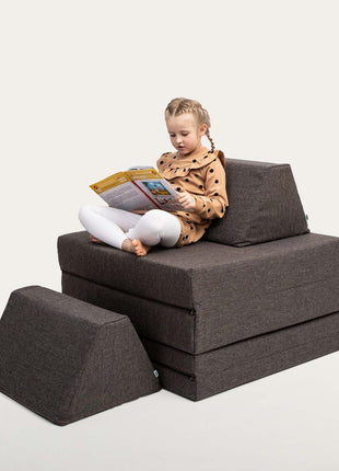 Kind zit comfortabel in hoge stoelvorm van de Monboxy Montessori speelbank – perfect als leeshoek voor peuters en kleuters.