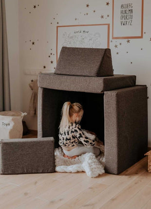 Kind speelt binnen een huisvormige constructie van de Monboxy Montessori speelbank – stimuleert rollenspel en verbeelding.