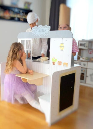 Kind speelt in de keuken van het Gerardo’s Toys 2-in-1 eetcafé, ander kind zit in het restaurantgedeelte.