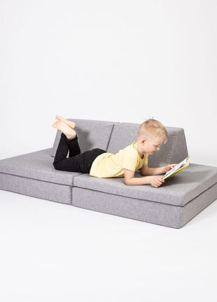 Kind ligt te lezen op de bankopstelling  van de Monboxy Montessori speelbank – stimuleert zelfstandige ontspanning.