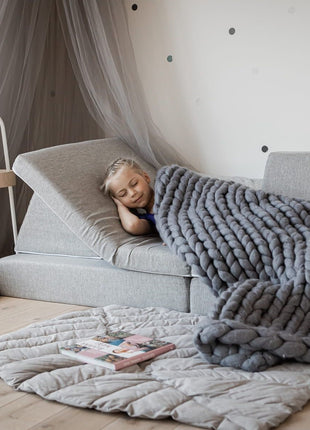 Kind slaapt op een grijze Monboxy Montessori speelbank onder een zachte deken – ideaal voor rustmomenten in de kinderkamer.