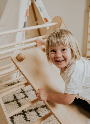 Kind glijdt van hellingbaan voor Pikler naturel bevestigd aan klimdriehoek