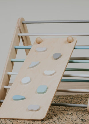 Hellingsbaan voor Pikler pastel bevestigd aan klimdriehoek met gekleurde grepen in lichte speelruimte