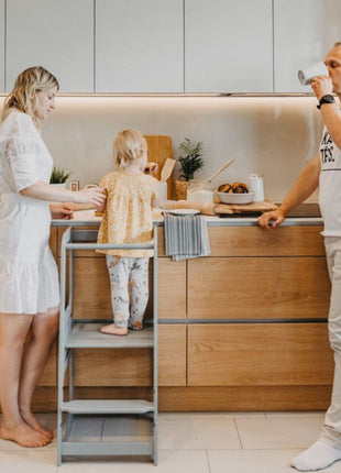 Grijze Keukenhulp Toren met kind aan aanrecht, twee volwassenen staan ernaast.