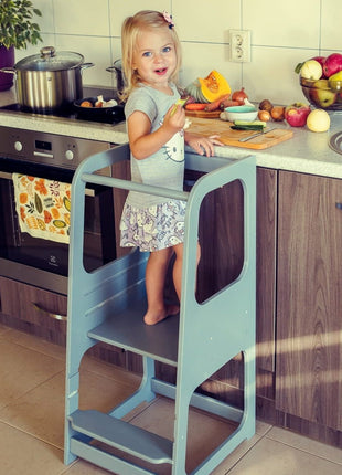 Grijze Keukenhulp Toren met kind dat groente snijdt aan aanrecht.