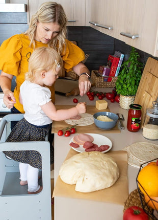 Keukenhulp Toren met kind dat met volwassene pizzatoppings plaatst op aanrecht.