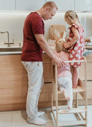 Keukenhulp Toren met kind dat opklimt terwijl ander kind en volwassene toekijken bij aanrecht.