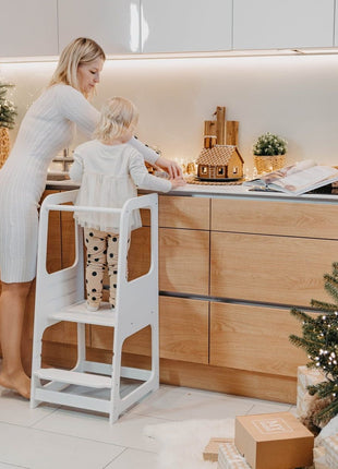 Witte Keukenhulp Toren met kind en volwassene die kersthuisje versieren.