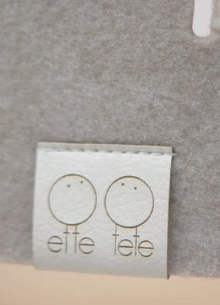 Detail van veiligheidsnet met Ette Tete logo label op lichtgrijs vilt