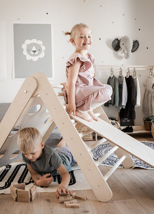 Twee kinderen spelen samen op klimdriehoek met helling – stimuleert fantasierijk en sociaal spel.