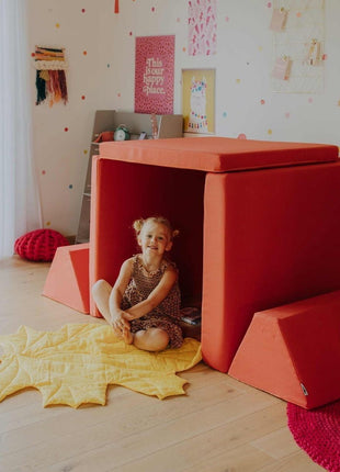 Kind zit ontspannen in speelhutopstelling van de Monboxy Montessori speelbank – comfortabele speelplek met kleed op de grond.
