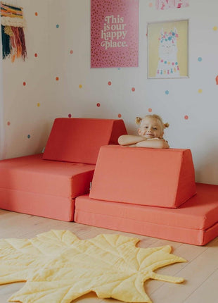 Kind speelt in een koraalkleurige Monboxy Montessori speelbank, ingericht als multifunctionele speelhoek.