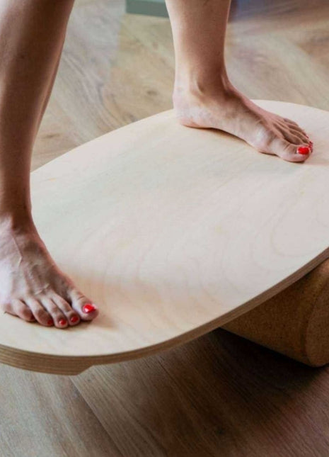 Blote voeten van volwassene op rond Leg&Go balansbord met kurkroller in woonkamer