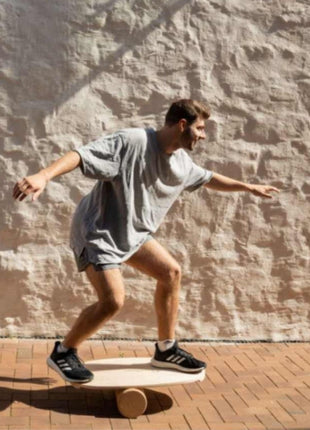 Volwassene balanceert op rond Leg&Go balansbord met roller op buitenterras