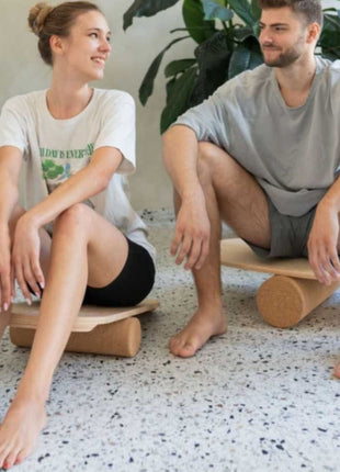 Twee volwassenen zitten op rond Leg&Go balansbord met kurkroller binnenshuis