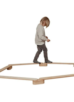 Kind balanceerd op de Leg&Go evenwichtsbalkenset van 6 in een zeshoekige opstelling.