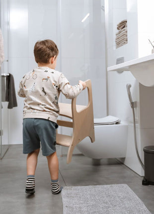 Kind draagt MIIMO in hoogte verstelbare opstap naturel naar de badkamer