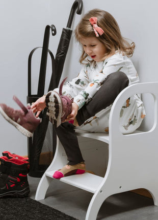 Kind trekt schoenen aan zittend op MIIMO in hoogte verstelbare opstap wit in de hal