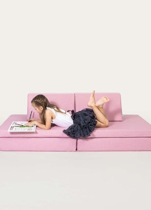 Kind tekent op een roze Monboxy speelbank in studio-opstelling, liggend op de mat.