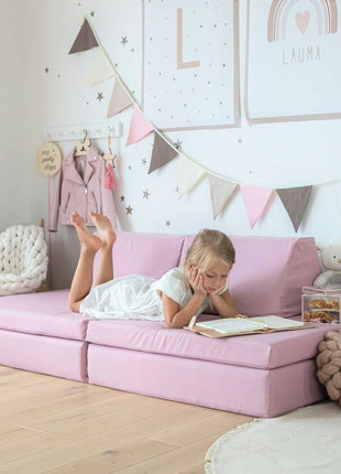 Meisje leest ontspannen op een roze Monboxy speelbank in een gezellige kinderkamer.