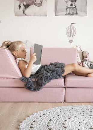 Meisje ontspant met boek op roze Monboxy speelbank in horizontale loungestand.