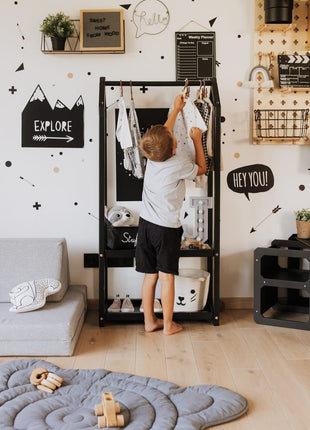 Jongen hangt kleding op Montessori Huisvormig Kledingrek in zwarte variant in kinderkamer.