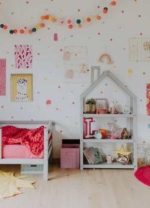 Grijze Montessori Huisvormige Plankenkast met speelgoed en decoratie in roze kinderkamer.