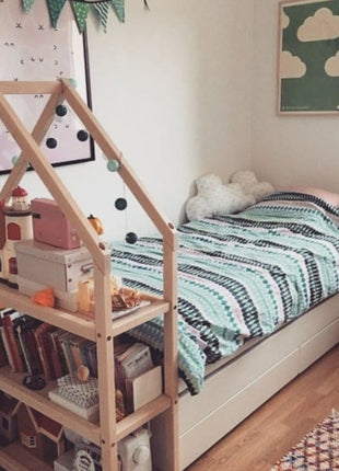 Montessori Huisvormige Plankenkast met boeken, speelgoedhuisjes en slinger in kinderkamer.