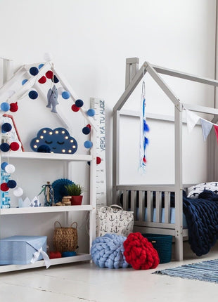 Witte Montessori Huisvormige Plankenkast met maritieme decoratie naast grijs huisbed.