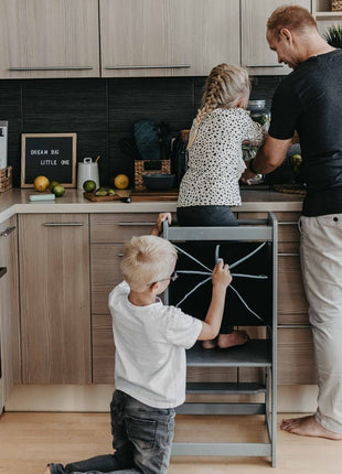 Montessori Keukenhulp met Schoolbord in grijs waarop kind kookt en ander kind tekent.