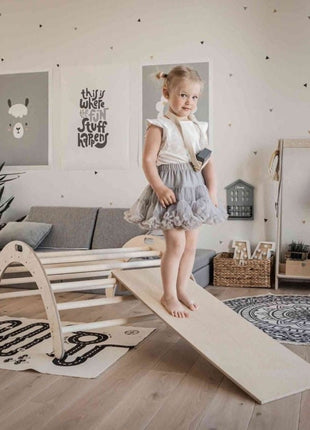 Kind staat bovenaan de helling van de Montessori Klimboog met Helling in een speelkamer.