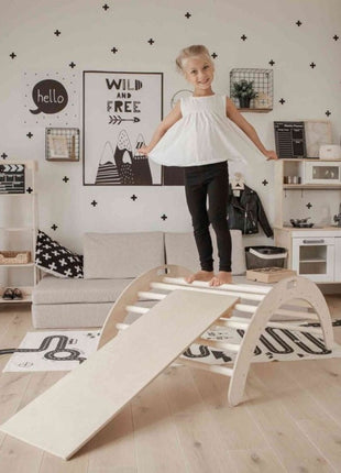 Kind staat bovenop de Montessori Klimboog met Helling in een Scandinavisch ingerichte speelkamer.