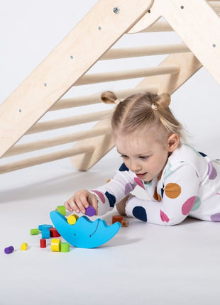 Meisje speelt met blokken onder het Montessori Klimrek op witte achtergrond.