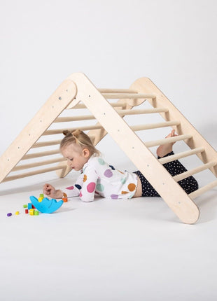 Meisje ligt onder het Montessori Klimrek  en speelt met blokken.