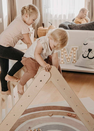 Twee kinderen klimmen op het Montessori Klimrek in een woonkamer.