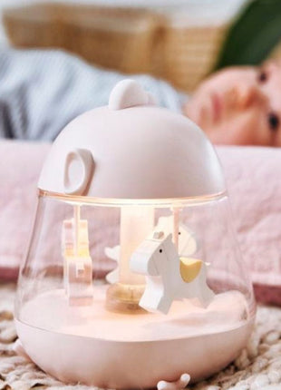 Montessori nachtlampje roze brandend met draaiende paarden, baby op achtergrond liggend.