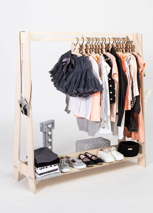 Montessori Peuterkledingrek in blank hout met peachkleurige en witte kleding op hangers.