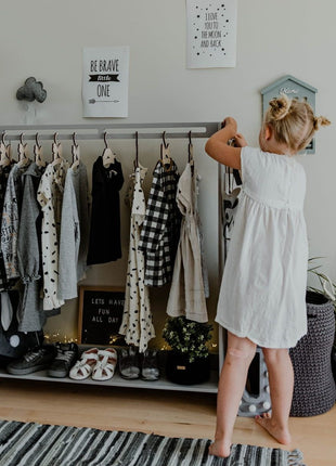 Meisje haalt kleding van Montessori Peuterkledingrek in kinderkamer.