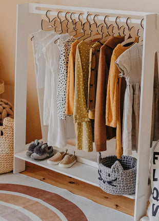 Montessori Peuterkledingrek in wit met opgehangen kinderkleding en schoenen eronder.