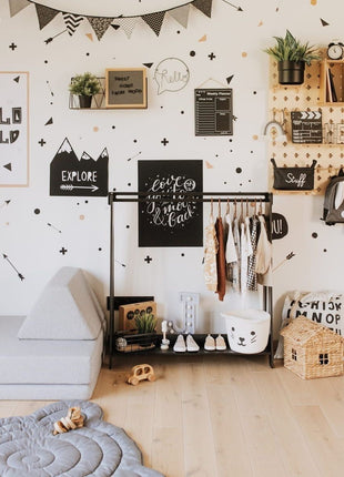 Zwarte Montessori Peuterkledingrek met kinderschoenen en kleding in modern interieur.